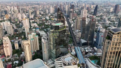 Video - Aerial drone view of Bangkok's business district with skyscrapers and the elevated BTS Skytrain railway running through the city Bangkok, Thailand - June, 6, 2025: