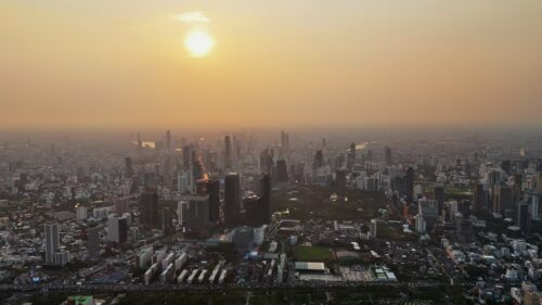 Video - Aerial drone view of Bangkok city skyline during sunset with warm golden light illuminating the dense metropolitan landscape
