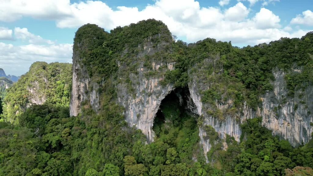Video - Aerial drone view of lush tropical jungle covering steep limestone karst mountains in southern Thailand
