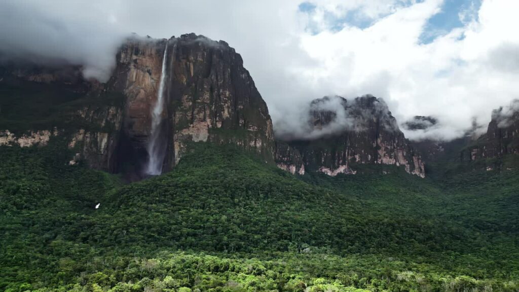 Video - Aerial drone view of Angel Falls flowing down the cliffs of Auyan-tepui with clouds drifting across the mountains in Canaima National Park, Venezuela