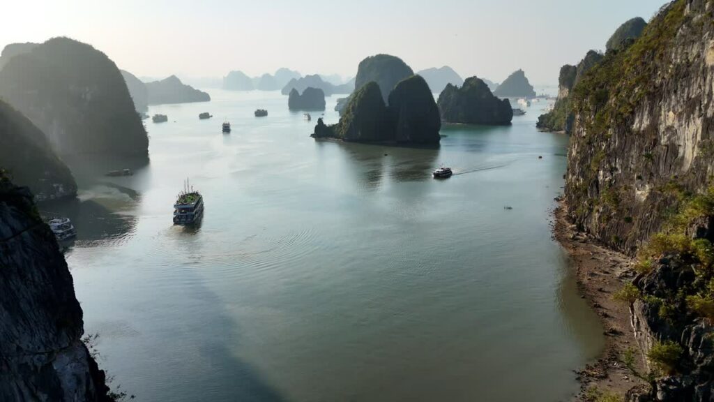 Video - Aerial drone view of boats sailing between limestone karst islands in Ha Long Bay, Vietnam, a UNESCO World Heritage site known for its spectacular seascape
