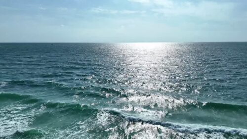 Video - Aerial drone view of sunlight reflecting on ocean waves creating sparkling patterns across the sea surface