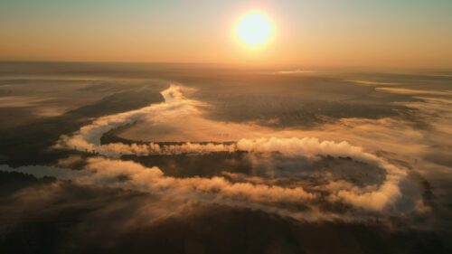 Video - Premium stock cinematic video footage - Aerial drone view of fog over a windy Nistru river at sunrise with red sky in Moldova