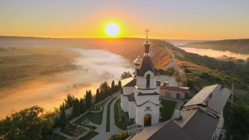Video - Aerial drone cinematic view of sunrise morning at Orheiul Vechi monastery with red sky and misty fog, dramatic epic shot
