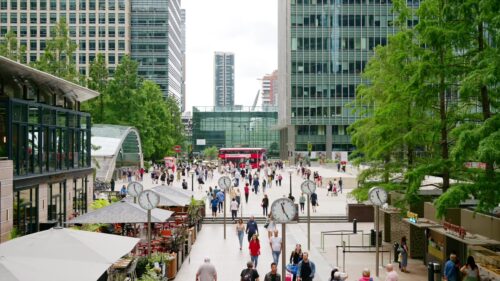 Video - LONDON, UNITED KINGDOM - SEPTEMBER 12, 2023: cinematic Street scape of the Canary Wharf district with Six Public Clocks square full of people and greenery, skyscrapers around