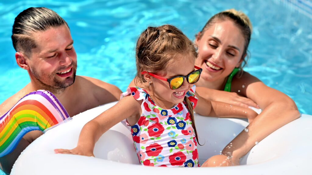 Happy parents and their daughter in rubber ring are swimming in the pool. Slow motion